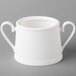 A white bone porcelain sugar bowl with a curved handle and lid.