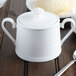 A white bone porcelain sugar bowl with a lid on a table.