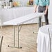 A man standing next to a Lancaster Table & Seating white folding table.