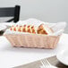 A white rectangular woven rattan-like basket filled with sliced bread on a table.