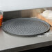 An American Metalcraft super perforated hard coat anodized aluminum pizza pan on a counter.