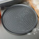 An American Metalcraft Super Perforated Hard Coat Anodized Aluminum Cutter Pizza Pan on a table next to a cutting board.