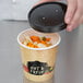 A hand holding a Choice paper soup cup filled with vegetables with the lid on top.
