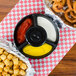 A black polypropylene tray filled with onion rings, fries, and dipping sauce on a table.