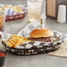 A black oval plastic fast food basket with a burger and fries.