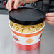 A hand opening a Choice paper soup container filled with pasta.