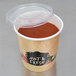 A Choice paper soup cup with a vented plastic lid on a counter with soup inside.