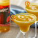 A bottle of DaVinci Gourmet Classic Habanero Flavoring Syrup on a table with two margaritas.