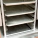 A Regency aluminum sheet pan rack with trays on shelves.
