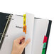 A hand inserting a multi-color Avery Index Maker divider set into a file folder.