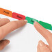A hand using a red and green Avery Index Maker tab on a colorful index card.