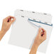 A pair of hands using Avery white index divider with clear label strip to point at a piece of paper.