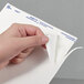 A person holding a piece of paper with a white Avery UltraDuty GHS label.