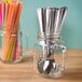 A Libbey County Fair mason jar with a spoon inside and colorful straws.