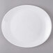 A white Arcoroc Zenix glass steak plate with a white rim on a gray surface.