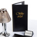 A black Menu Solutions wine list cover on a table with a lamp.