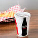 A Solo paper cold cup with a straw and a basket of fries.
