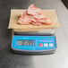 A AvaWeigh digital portion scale with meat on it.