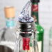 A clear bottle with a red Tablecraft Proper Pour spout on it.