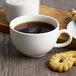 A Villeroy & Boch white porcelain cup of coffee with cookies on a wooden table.