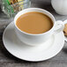 A close-up of a white Villeroy & Boch porcelain cup of coffee on a saucer with a cookie.