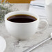 A close-up of a white Villeroy & Boch porcelain cup filled with coffee on a saucer.