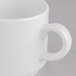 A close-up of a Villeroy & Boch white porcelain stackable cup with a white handle.