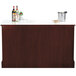 A Bon Chef portable wood back bar with bottles and glasses on top.