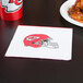 A Creative Converting Kansas City Chiefs luncheon napkin with a red helmet and white logo on it next to a plate of chicken wings.