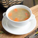 A white porcelain soup cup filled with soup and carrots.