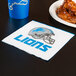 A Detroit Lions luncheon napkin with a logo on it next to a plate of chicken wings.