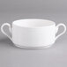 A white Villeroy & Boch porcelain soup bowl with two handles on a gray surface.
