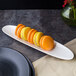 A white Villeroy & Boch porcelain boat filled with colorful macarons on a table.