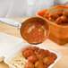 A Vollrath black perforated round Spoodle spoon serving spaghetti with meatballs.