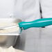 A person using a Vollrath teal Perforated Oval Spoodle to serve food.