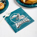 A plastic fork on a Philadelphia Eagles luncheon napkin with a plate of food.