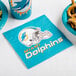 A blue Miami Dolphins luncheon napkin on a table with pretzels and a football helmet.