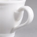 A close-up of a white Villeroy & Boch porcelain cup with a handle.