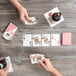 A group of people playing cards with a "Bee" Jumbo Font deck on a wood table.