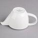 A white porcelain teapot with a handle and spout.