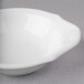 A Villeroy & Boch white porcelain oval bowl with a curved edge on a gray surface.