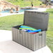A Lifetime grey plastic outdoor storage box filled with pool noodles and swimming pool toys.