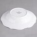 A white porcelain soup plate with a scalloped edge.