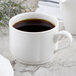 A Villeroy & Boch white porcelain stackable cup on a table with black coffee in it.