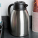 A black insulated thermal coffee carafe with a brew thru lid.