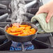 A Choice 6" mini cast iron skillet filled with cooked carrots on a stove.