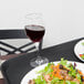 A Carlisle Griptite non skid tray holding a salad and a glass of wine on a table.
