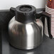 A silver and black Choice insulated thermal coffee carafe with a brew thru lid on a counter.