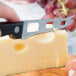 A person cutting cheese with a Franmara serrated cheese knife.