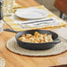 A Choice pre-seasoned cast iron skillet with potatoes on it on a wooden table.